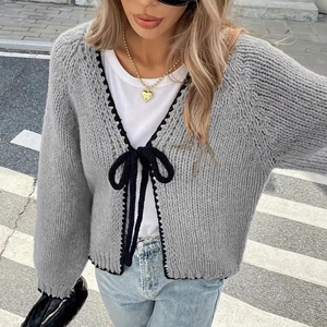 Detail of grey chunky knit cardigan with black crochet trim and bow tie closures