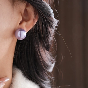 Close-up of large purple pearl stud earrings on a model with French vintage style