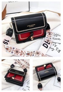 Detail view of black crossbody bag with red trim, tassel hardware and ethnic strap