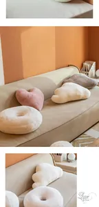 Plush heart, cloud and donut shaped throw pillows on a beige sofa in a cozy room
