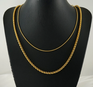 Close-up of two different gold stainless steel chain necklaces on a black neck bust
