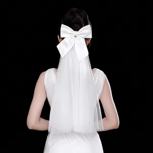 Macro shot of double-layered white bridal veil with large satin bow and soft mesh texture