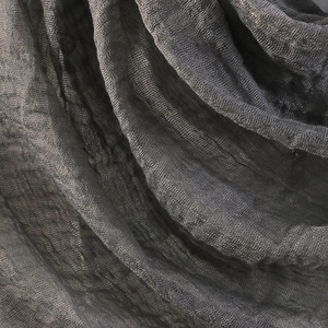 Detailed close-up of dark grey crinkle texture on cotton linen scarf fabric with raw edges