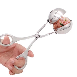 Detailed close-up of a stainless steel meat baller tool holding a perfectly shaped meatball