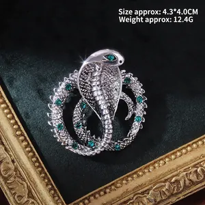 Detailed macro view of vintage silver cobra brooch with green rhinestones on velvet