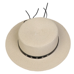 Detail view of woven straw hat featuring black band with metallic star studs