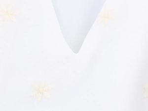 Detail des V-Ausschnitts mit eleganten Blumenstickereien auf weißem Webstoff