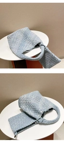 Detail of light blue woven denim tote with knotted handle design on a white table