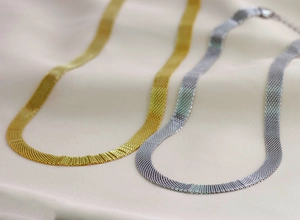 Detailed macro view of 8mm mesh woven necklaces in gold and silver over silk