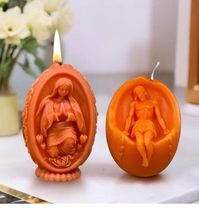 Detail von brennenden orangefarbenen Osterkerzen mit Maria und Jesus Reliefschnitzereien