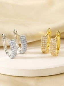 Detailed view of gold and silver hoop earrings with clear pave crystals on beige stand