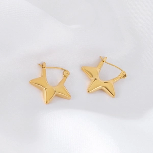 Detailed close-up of golden pentagram hoop earrings on white silk background texture