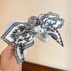 Close-up of vintage paisley pattern fabric bow hair clip with detailed textile texture
