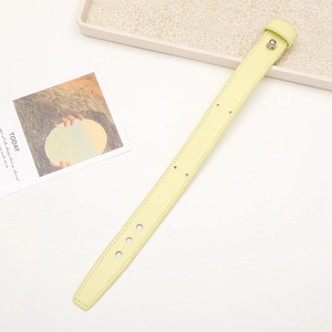 Detail of yellow leather phone wrist strap with metal buckle and adjustable holes on desk
