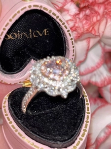 Vista macro di anello d'argento con halo di diamante rosa in confezione a cuore