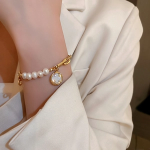 Close-up of fresh water pearl bracelet with gold smiley pendant on woman wrist