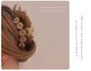 Detail of peach hair claw clip with pink fruit accents styled on long brown hair