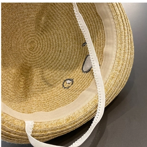 Detailed interior of straw sun hat showing soft sweatband and white lace wind strap