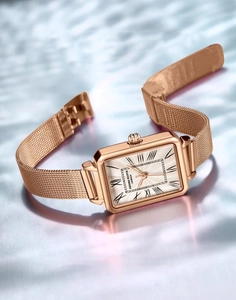 Detailed view of luxury women's rose gold square watch with Roman numerals and mesh band
