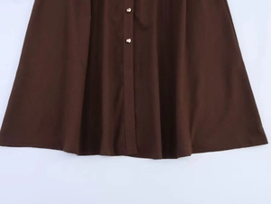 Dettaglio dell'orlo dell'abito a camicia in lino marrone scuro con abbottonatura frontale