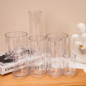 Set of transparent cylindrical molds in various sizes for DIY candle making on wooden base