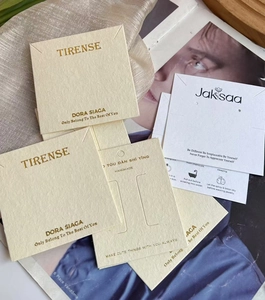 Close-up of elegant cream and white jewelry display cards with gold foil lettering