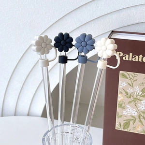 Detail of colorful daisy flower straw toppers on glass straws in a stylish setup