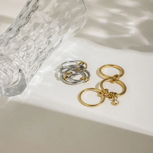 Détail de bagues multicouches en acier inoxydable avec pendentif zircon et reflets d'eau