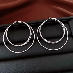 Vue détaillée de boucles d'oreilles créoles argentées avec texture diamantée sur cuir noir