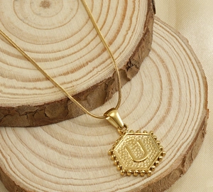 Détail du pendentif hexagonal en or 18k avec lettre U sur une chaîne de serpent