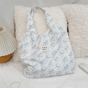 Détail d'un sac cabas en toile blanche avec motif ours mignon et fleurs bleues