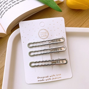 Three silver wavy Y2K metal hair clips on a white display card with floral background