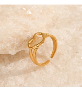 Macro detail of golden heart cut-out ring on textured natural white stone background