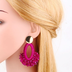 Detail of rose red beaded embroidery earrings with bohemian fan fringe and gold studs