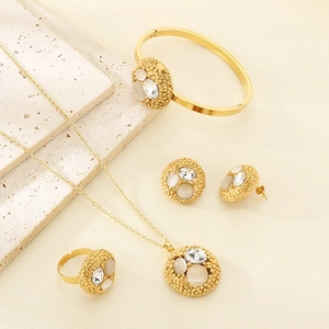 Luxe gold-plated jewelry set with micro-pave zircon pendants on beige stone background