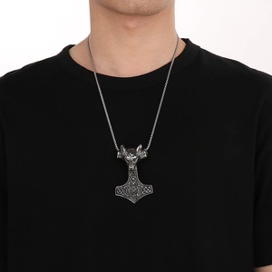 Gros plan d'un pendentif Mjölnir en argent avec tête de loup sur le cou du mannequin