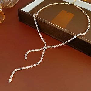 Close-up of golden Y-shaped necklace with drop tassels and clear olive-cut gemstones