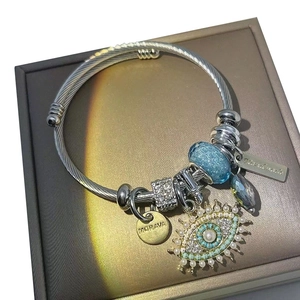 Detailed shot of evil eye charms and beaded pendants on a twisted silver bangle