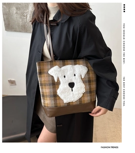 Detail view of checkered tote bag with plush dog motif and brown leather straps