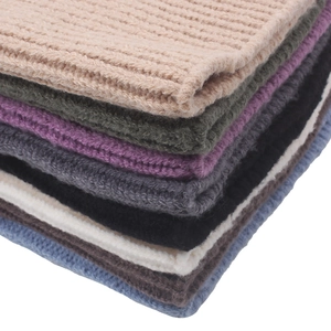 Macro shot of knitted texture and colorful stack of warm winter beanies