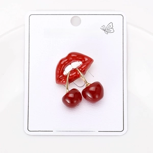 Macro shot of stylish red enamel cherry lip earrings with gold hooks on a jewelry card