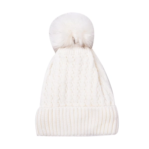 Close-up of white knit beanie featuring thick cable patterns and large faux fur pom-pom