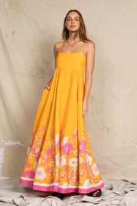 Detail of a flowy yellow maxi dress featuring pink floral prints and a delicate A-line hemline
