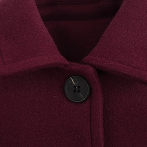 Close-up of lapel detail and black button on burgundy wool blend coat fabric
