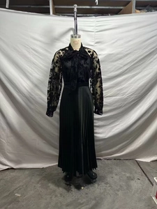 Detail of elegant black long-sleeve dress with lace bodice, bow tie neck and pleated skirt
