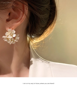 Dettaglio degli orecchini floreali a C con petali bianchi e diamanti indossati da una modella