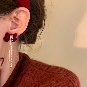 Detail of red velvet bow earrings with sparkling rhinestone tassels on model