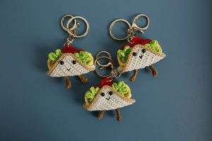 Detailed close-up of handmade crochet taco keychains with textured yarn and golden rings