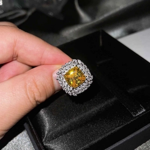 Close-up of luxury Asscher cut yellow diamond ring held against black jewelry box