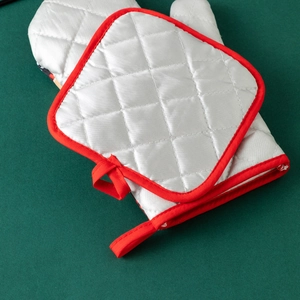 Silver quilted oven mitt and square pot holder with red trim on dark background